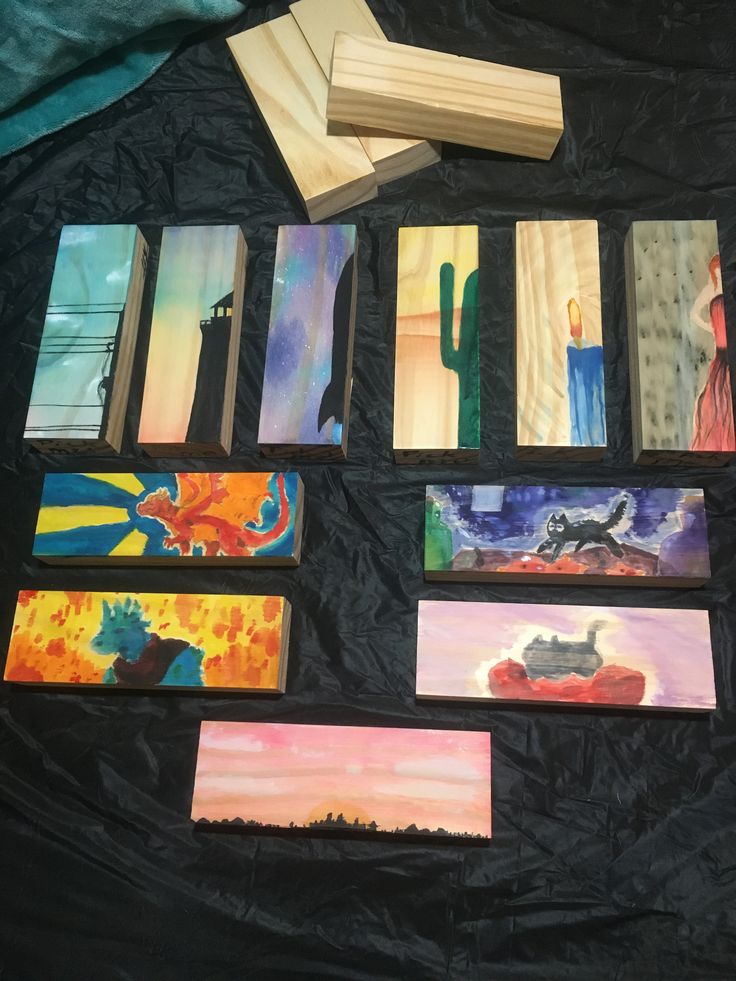 several paintings are laid out on a black sheet and one has a piece of wood sticking out of it