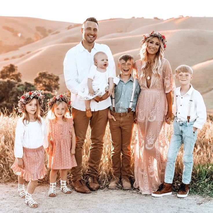 a family posing for a photo in front of some hills and grass with the sun shining on them