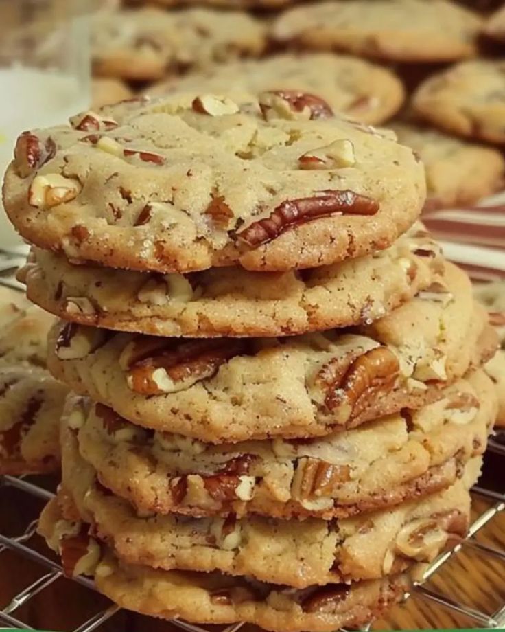 a stack of pecan cookies sitting on top of a cooling rack next to a glass of milk