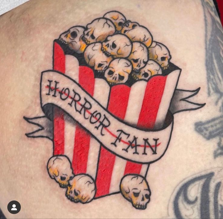 a close up of a person with a tattoo on his arm and chest holding a box of popcorn