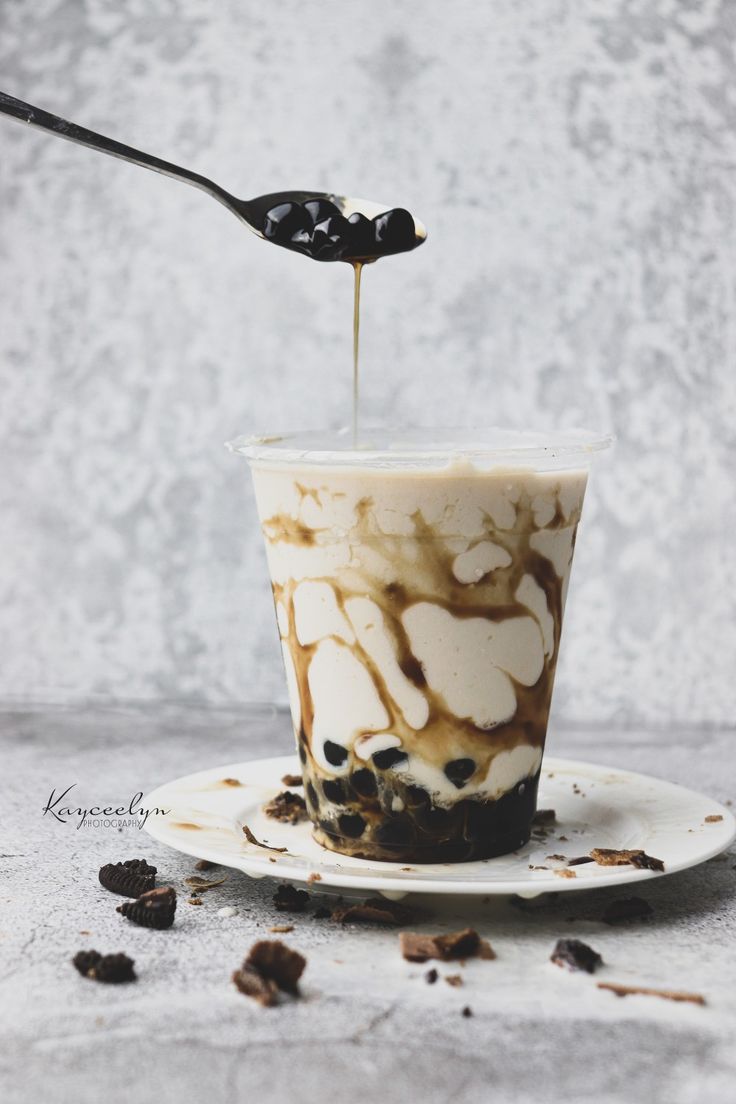 a spoon is pouring coffee into a cup