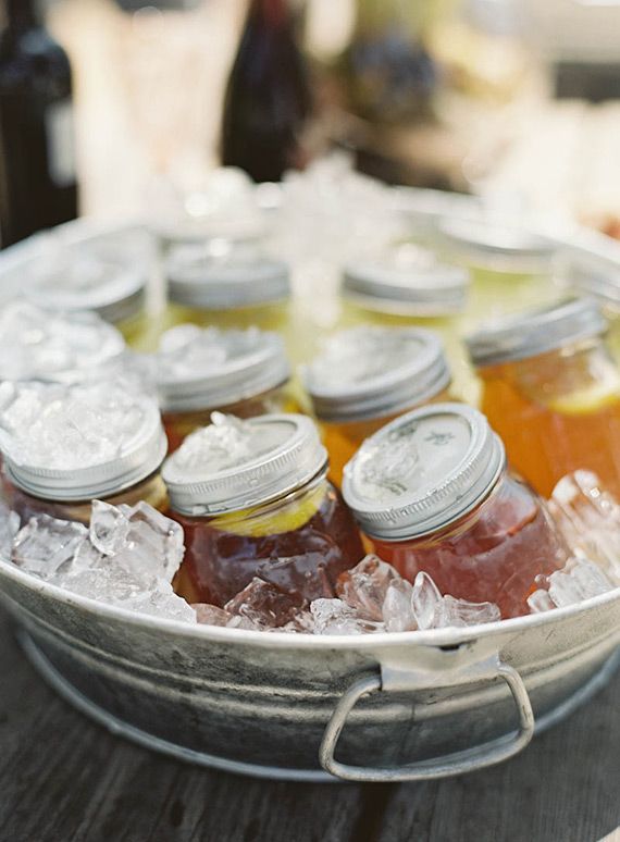 there are many jars and spoons with honey on the table next to each other