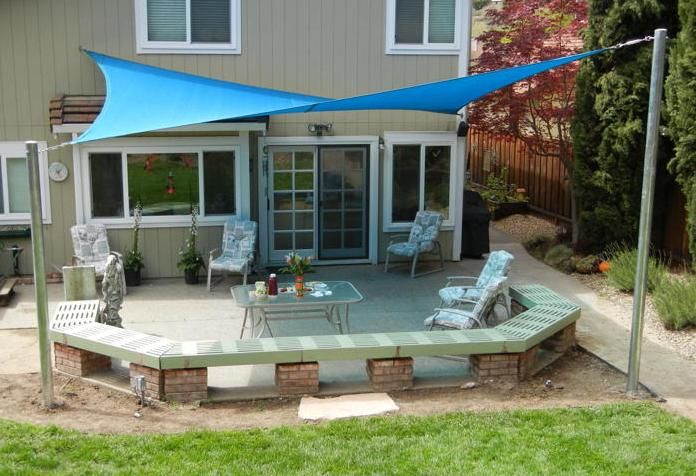 a patio with chairs and a table under a blue awning in front of a house