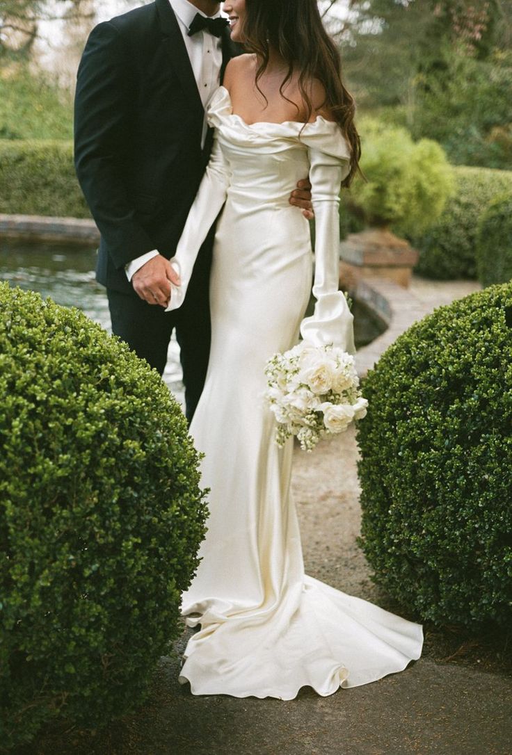 a bride and groom standing in front of some bushes