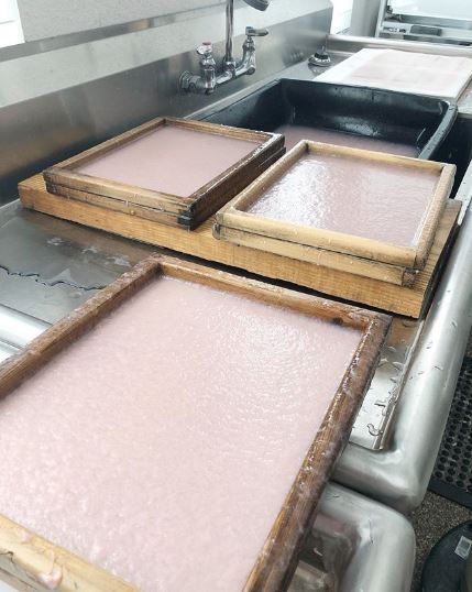 three wooden trays sitting on top of a metal counter next to a sink and faucet