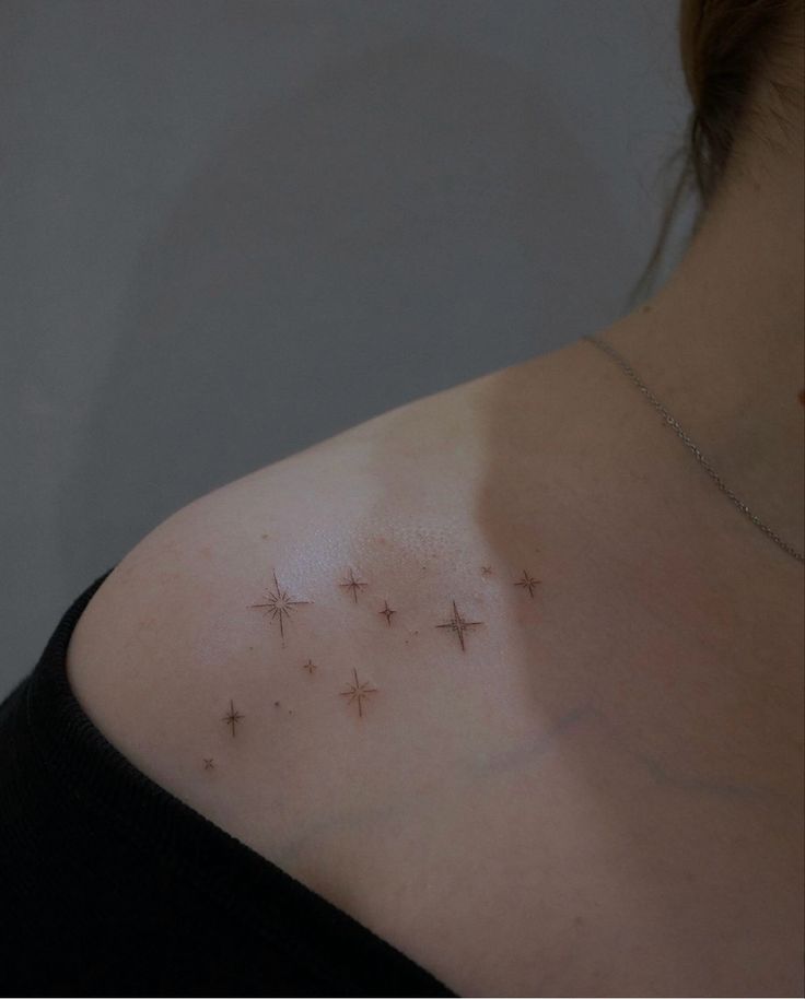 the back of a woman's shoulder with small stars on her left arm and chest