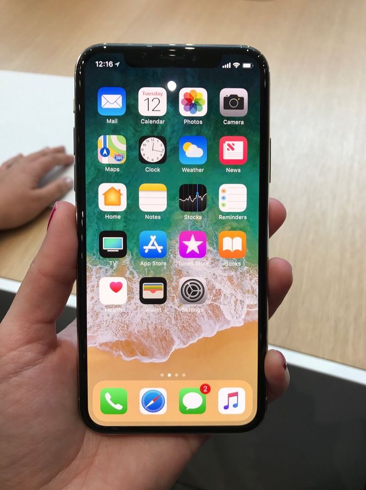 someone holding an iphone in their hand with the screen showing icons on it, near a computer keyboard