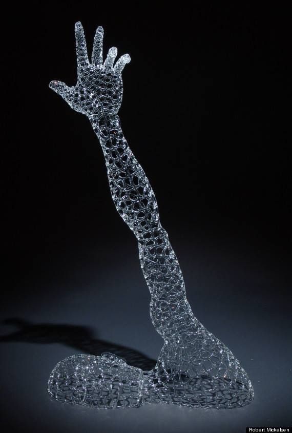 a glass sculpture of a hand reaching up into the air with it's fingers