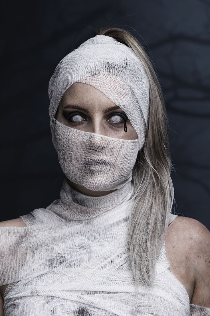 a woman with bandages wrapped around her head and eyes, wearing a bandaged white dress