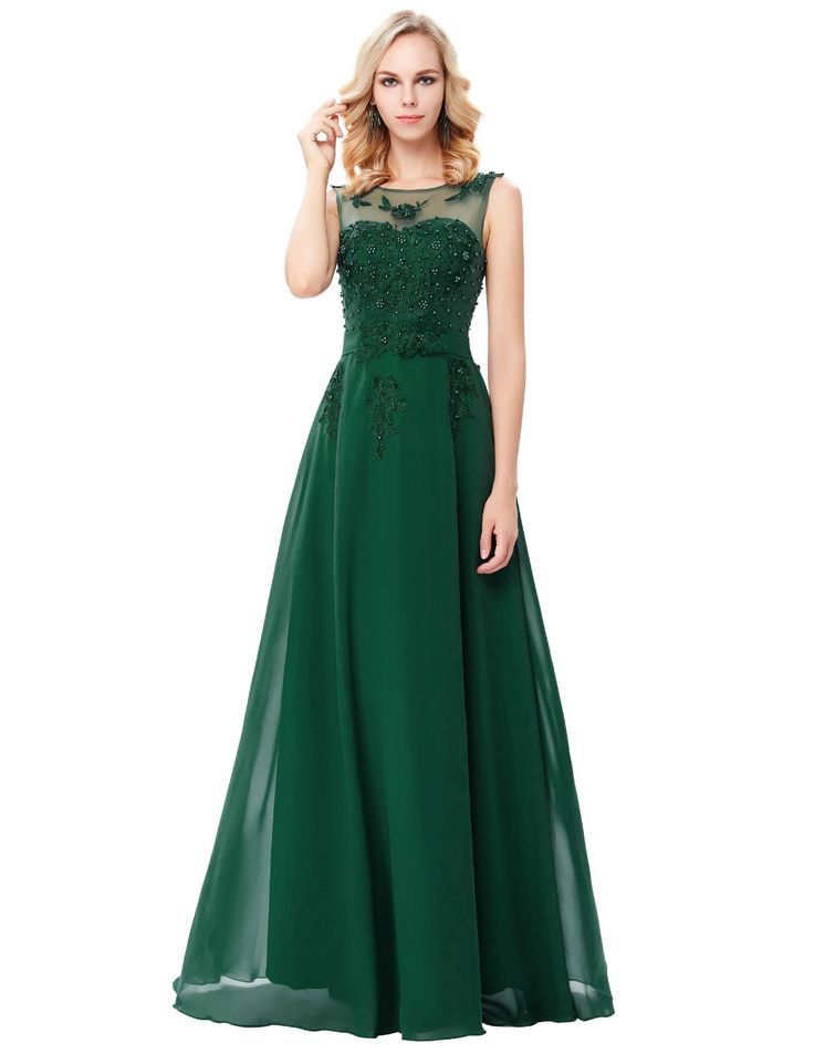 a woman in a long green dress with lace on the top and bottom, standing against a