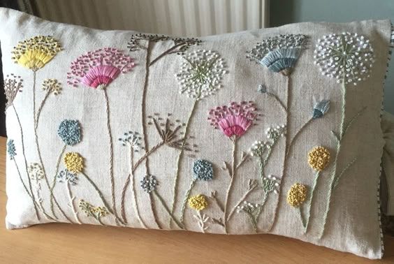 a white pillow with flowers on it sitting on a wooden table next to a radiator