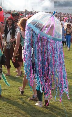 a group of people standing in the grass near a jellyfish tent with streamers hanging from it