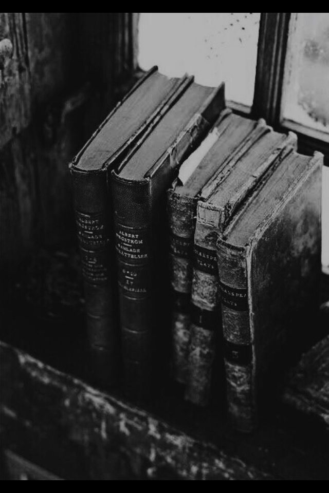 several old books are sitting on a shelf in front of a framed picture and window