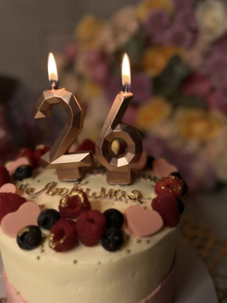 a birthday cake with two lit candles on it