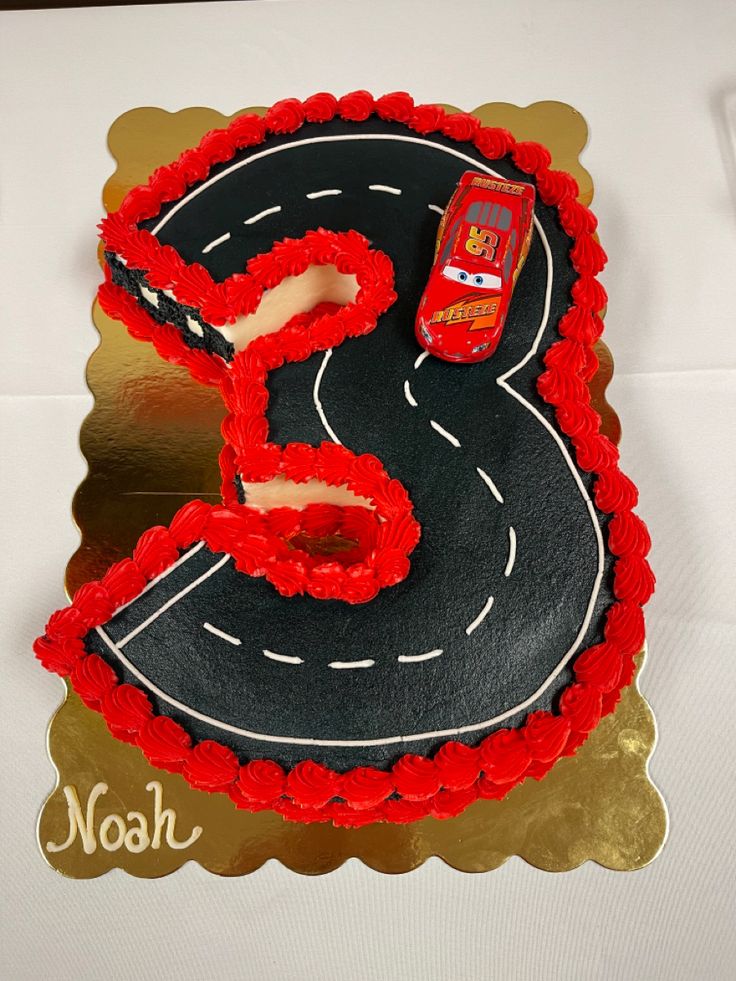 a birthday cake that is shaped to look like the number 5 on a road with cars