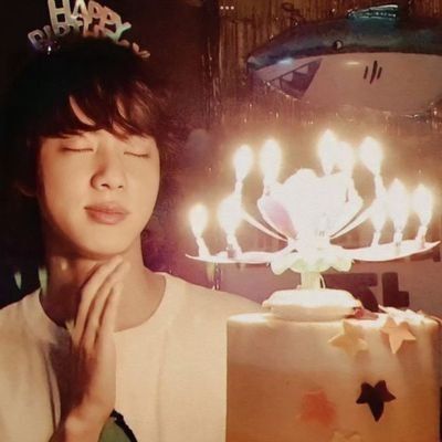 a young person standing in front of a cake with candles on it