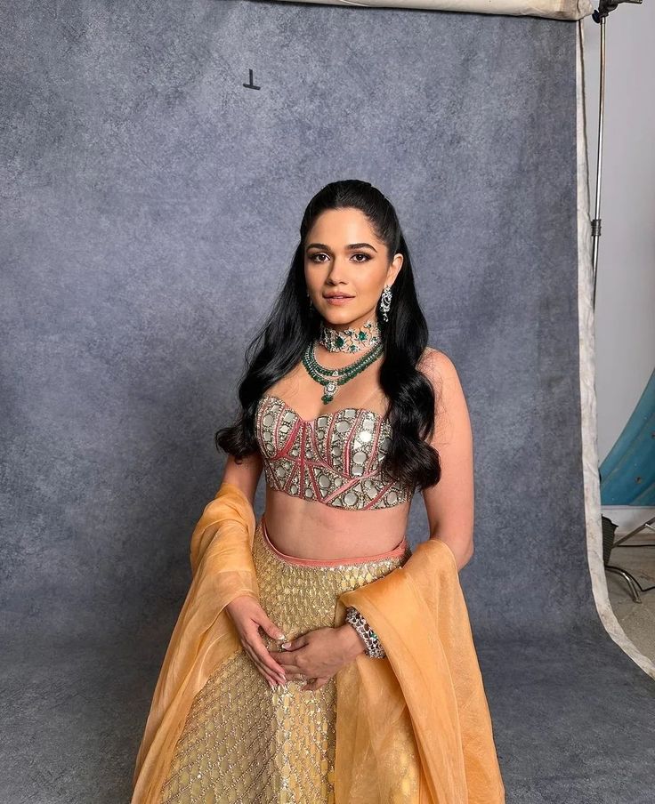 a woman in a yellow and gold lehenga posing for the camera with her hands on her hips