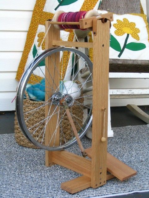 an old spinning wheel is sitting on the ground in front of a quilter's wheel