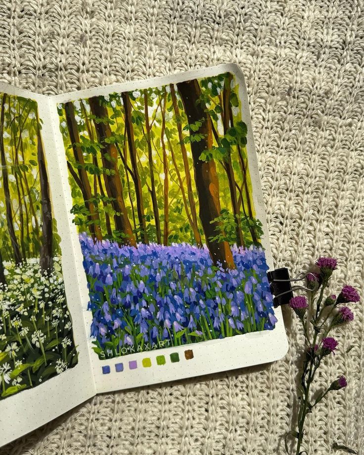 an open photo album with bluebells and wildflowers in the woods next to it