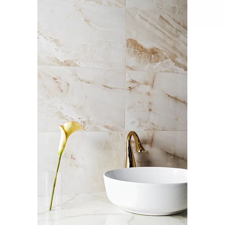 a white bowl sitting on top of a counter next to a vase with flowers in it