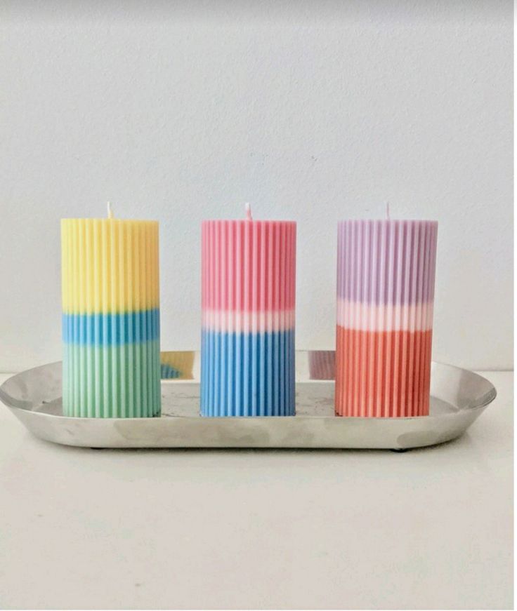 three multicolored candles sitting on a tray