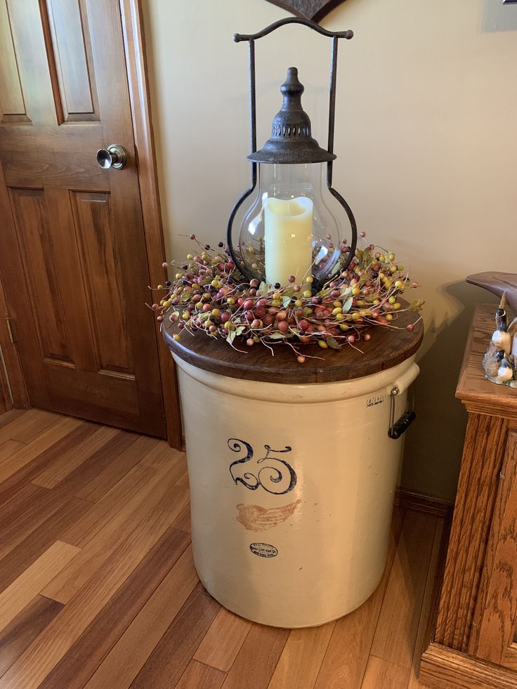 an old fashioned ice bucket with a candle and some candy in it sitting on the floor