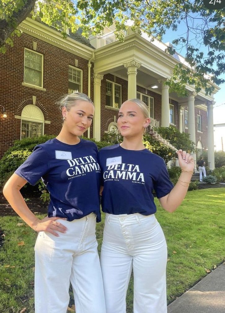 two women standing next to each other in front of a house