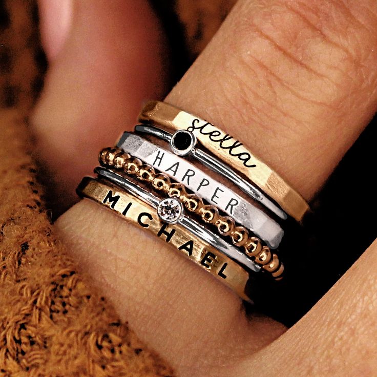 Personalized stackable ring set, engraved with names, dates, or special words. All 6 rings shown in the photos are included in this listing.  Choose between mixed metals, fine silver, or 14K yellow gold-filled for your set! MIXED METALS include: 2 - yellow gold-filled name rings 1 - fine silver name ring 2- sterling silver birthstone rings 1 - yellow gold-filled beaded ring This ring set includes three name rings, a beaded ring, and two cz rings Metal: 14k gold filled, .999 fine silver, .925 sterling silver Dimensions: name rings are 2mm tall on average, but our rings are handmade so variations will occur. The beaded ring is 2mm, and the birthstones are 2mm on a 1mm band (one sterling silver, one 14k gold filled). Font: lowercase cursive, uppercase thin block, uppercase thick block Unsure Personalized Stackable Rings, Stackable Name Rings, Stacked Rings, Grandmother Jewelry, Rings Stacking, Necklace Combo, Ring Cuts, Ring Spacer, Name Ring