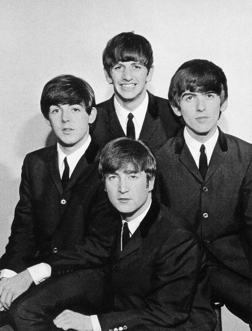 the beatles posing for a black and white photo in suits with their heads turned to the side