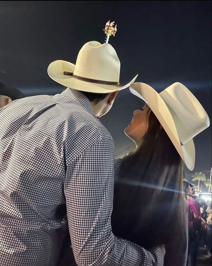 a man and woman in cowboy hats standing next to each other at an outdoor event