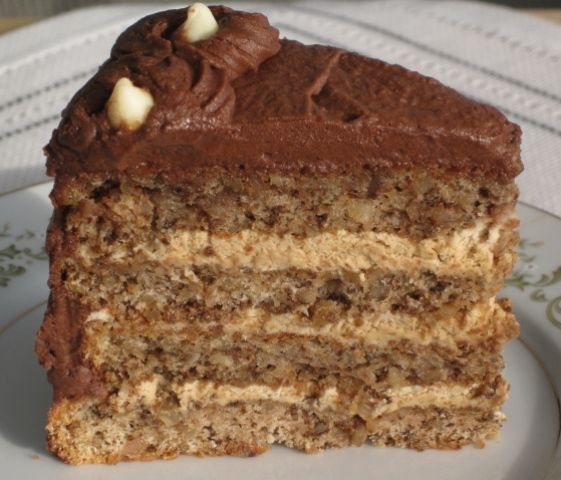 a piece of cake with chocolate frosting and walnuts on top is sitting on a plate