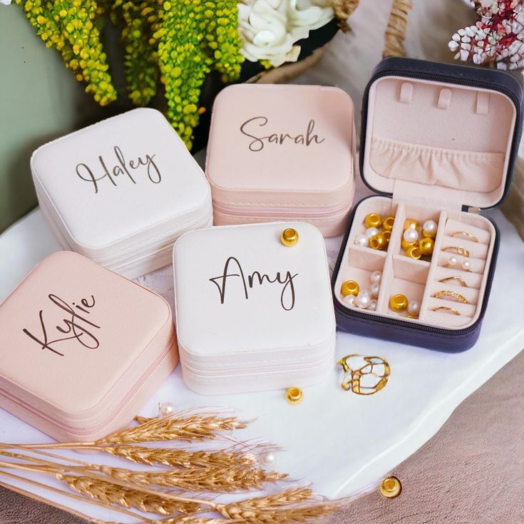 four personalized jewelry boxes sitting on top of a table with flowers in the background