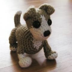 a small crocheted dog is standing on the floor