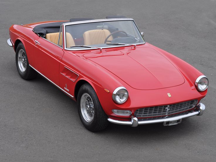 an old red sports car is parked in a parking lot with the top down and it's hood up