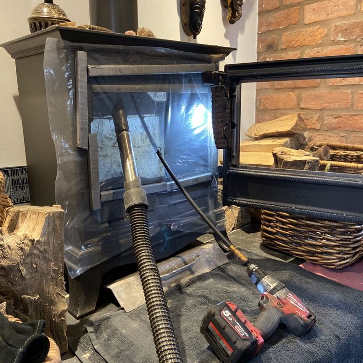 a vacuum is sitting on the floor in front of a fire place and some logs