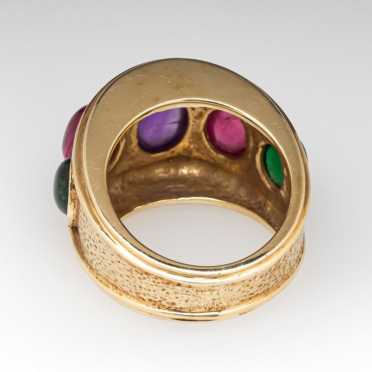 This beautiful ring is centered with one (1), bezel set, oval cabochon cut natural amethyst and is flanked to each side by one (1), bezel set, oval cabochon cut natural pink tourmaline and one (1), bezel set, oval cabochon cut natural green tourmaline. The ring measures 16.1mm at the top, rises 9.0mm above the finger, tapering to 7.1mm wide and 1.5mm thick at the base of the shank. It is currently a size 6.5. Yellow Gold Multi-stone Cabochons For Fine Jewelry, Yellow Gold Multi-stone Cabochons Fine Jewelry, Luxury Multi-stone Oval Cabochons, Formal Multi-stone Oval Cabochon Gemstones, Fine Jewelry Domed Gemstone Cabochons, Domed Gemstone Cabochons Fine Jewelry, Formal Rings With Bezel Setting And Oval Cabochon, Yellow Gold Multi-stone Oval Cabochon Gemstones, Fine Jewelry Round Cabochons With Bezel Setting