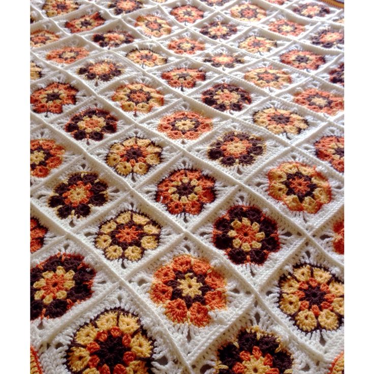 a crocheted blanket with orange and brown flowers