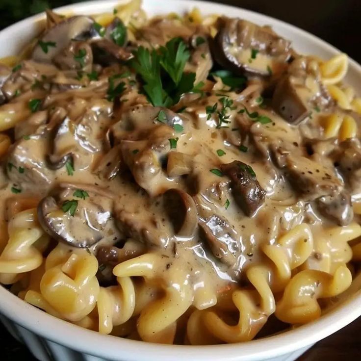 a white bowl filled with pasta covered in mushroom sauce