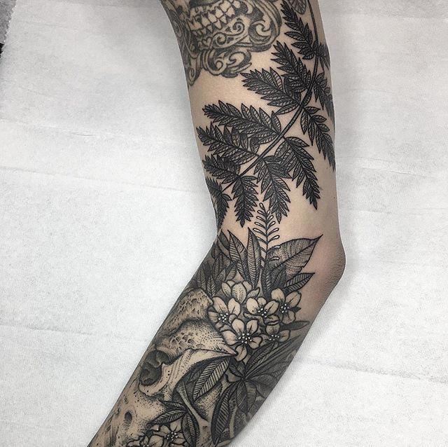 a woman's leg with tattoos and flowers on it