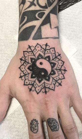 a person's hand with a tattoo on it and a yin symbol in the middle