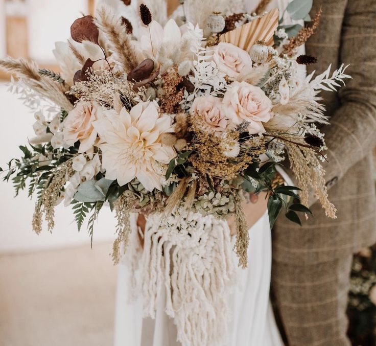 the bride and groom are holding their bouquets in front of each other with feathers on them