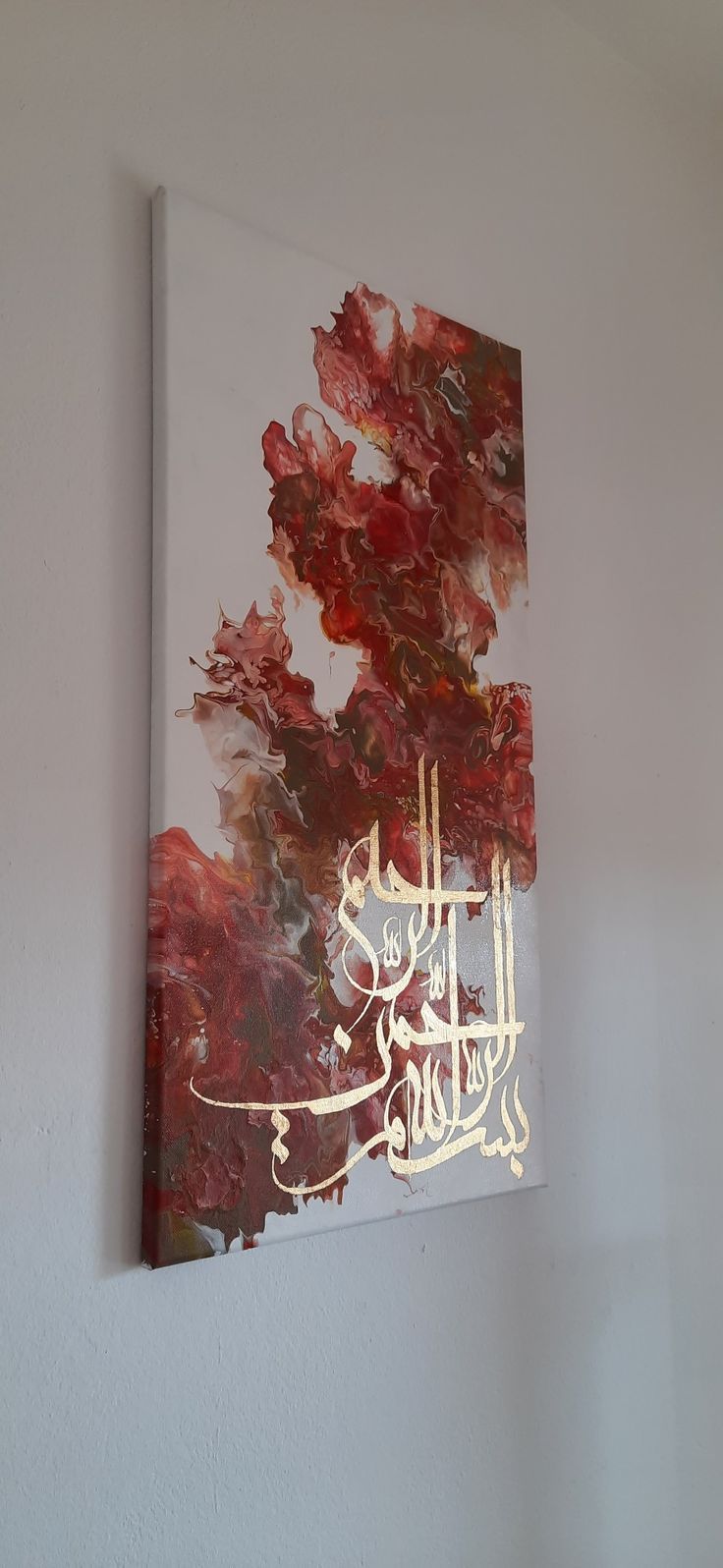 a painting hanging on the wall in an empty room with white walls and red flowers