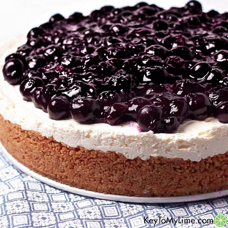 a blueberry cheesecake on a white plate with a blue and white table cloth