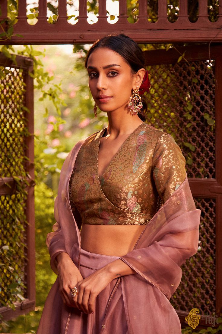 "Lakshmi\nA regal set\u00a0with old-world grandeur,\u00a0combined with modern-day effortlessness. A glorious full-ghera silken lehenga skirt, paired with an exquisitely handwoven satin tissue brocade blouse. Set against\u00a0the soft, fleeting romance of\u00a0intricate floral hand-embroidery on pure gossamer organza.\n\u00a0\n\n\n\n Color\u00a0-\u00a0A\u00a0blouse in a beautifully shimmering\u00a0shade of\u00a0Olive Green, skirt and odhani in a Dusty Pink\n\n Fabric\u00a0- Pure Satin Silk Tissue Brocade Handwoven Blouse,\u00a0Pure Silk Skirt and Pure Silk Organza Odhani\n\n Speciality\u00a0-\u00a0An extraordinary visual and an effortless silhouette. Beautifully handwoven in lush satin silk tissue with multicoloured tanchoi meenakari, glorious peacocks adorn the\u00a0statement angarakha-sty Banarasi Saree Blouse, Banarasi Blouse, Brocade Blouse Designs, Brocade Lehenga, Brocade Saree, Simple Lehenga, Bridesmaid Saree, Latest Model Blouse Designs, Traditional Dresses Designs