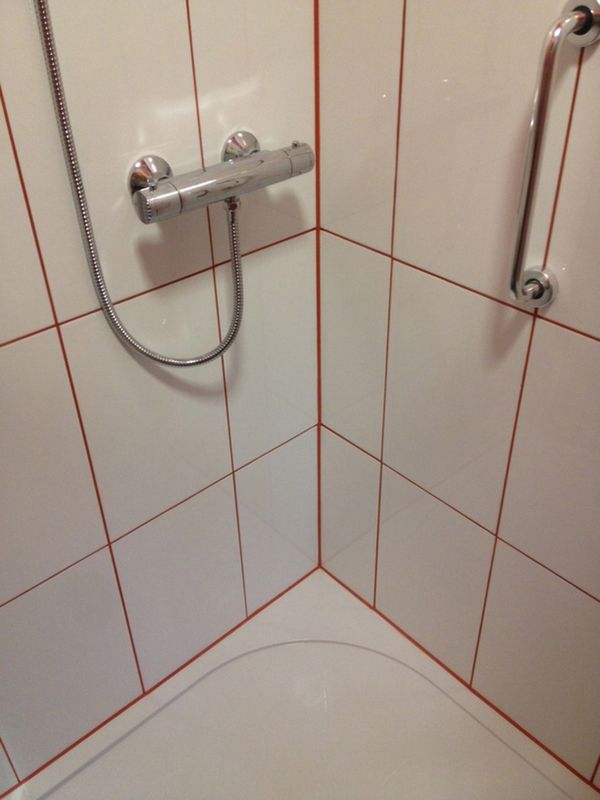 the shower head is connected to the faucet in this tiled bathtub with red and white tiles