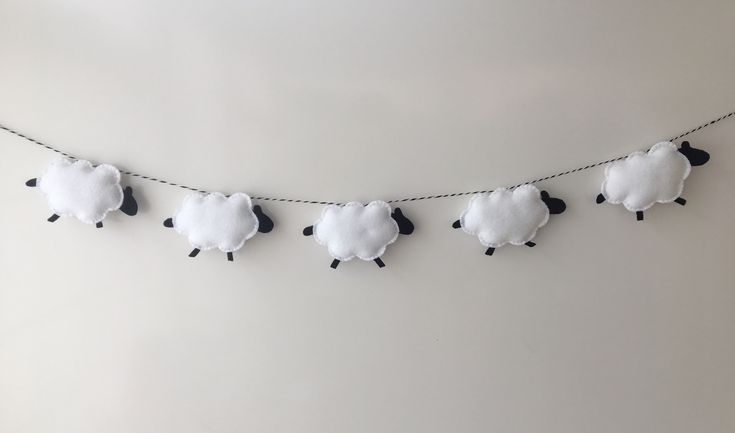 there are five sheep hanging on the line with black and white ones in front of them