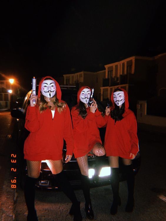 three women in red hoodies and masks are sitting on the back of a car