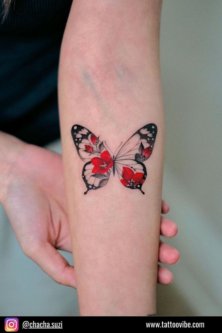 a woman's arm with a red and black butterfly tattoo on the left forearm