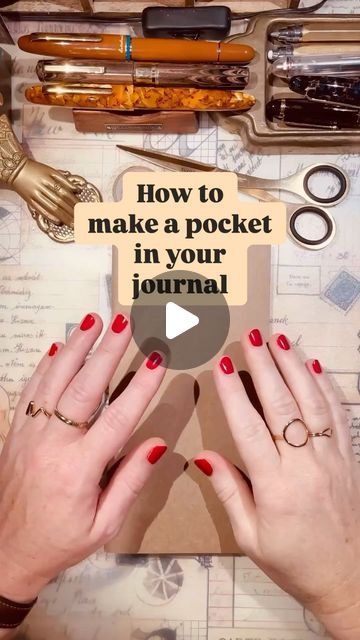 two hands on top of a table with scissors and other items in the background that says how to make a pocket in your journal