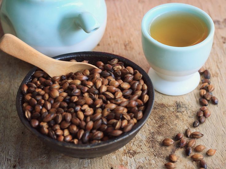 a bowl of coffee beans next to a cup of tea